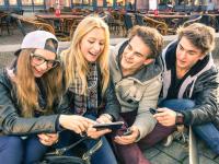 Vier Teenager betrachten Inhalte auf einem Smartphone