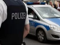 Foto eines Polizisten in Schutzweste vor Polizeiautos
