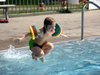 Kind mit Schwimmflügeln im Schwimmbad