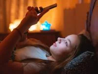 Mädchen schaut alleine in ein Smartphone