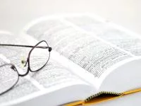 Foto einer Brille auf einem aufgeschlagenen Buch