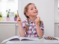 Mädchen sitzt mit Lernmaterial am Schreibtisch