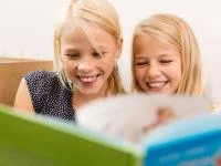 Lächelnde Mädchen lesen gemeinsam ein Buch