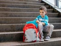 Foto eines kleinen Jungen mit seinem Ranzen auf einer Treppe