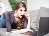 Frau schaut entgeistert auf Laptop
