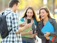 Gruppe lacht gemeinsam über Smartphone-Inhalt
