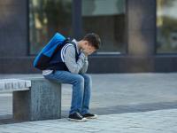 Schüler sitzt alleine im Freien