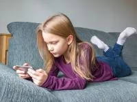 Ein Mädchen mit Smartphone auf dem Sofa