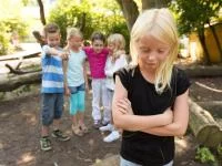 Ein Kind steht allein, alle Anderen lachen es aus
