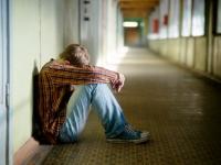 Ein Junge sitzt zusammengesunken im Schulflur