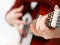 Kinderhände halten eine Gitarre